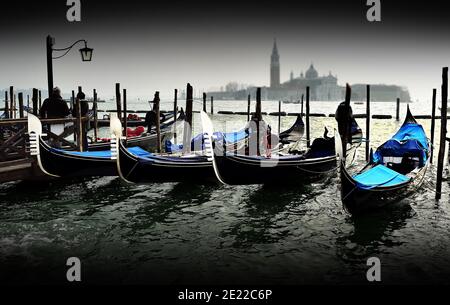 VENISE, ITALIE - 09 février 2016 : quatre gondoles amarrées et en attente d'affaires à Venise, Venise, Italie, avec mer calme et bâtiments dans la distanc Banque D'Images