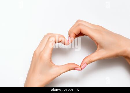 Une jeune femme à la main montre un signe de coeur sur un fond gris. Concept pour la Saint-Valentin, l'amour, la romotique. Espace de copie de la vue de dessus. Banque D'Images