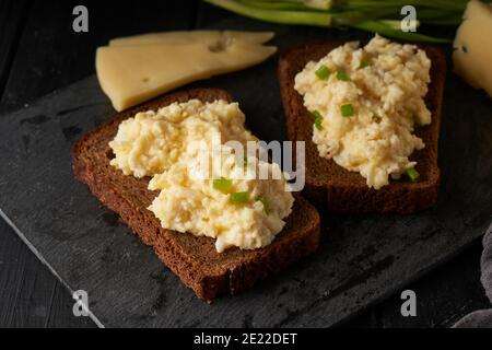 Œufs brouillés avec oignon vert et pain sans gluten table noire Banque D'Images