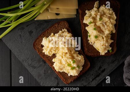 Œufs brouillés avec oignon vert et pain sans gluten table noire Banque D'Images