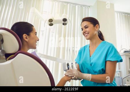 La dentiste féminine en soutien à la patiente tient la main de la patiente la plaçant dans un positif. Banque D'Images