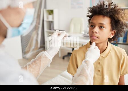 Vue arrière chez un médecin méconnaissable qui a passé un test covid Garçon afro-américain en clinique médicale Banque D'Images