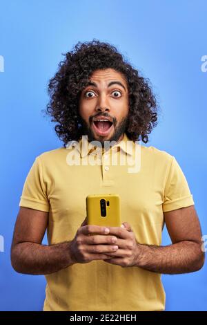 un jeune homme choqué tient utiliser smartphone lire a reçu une notification comme scream omg, il est surpris par les nouvelles ou le message, isolé Banque D'Images