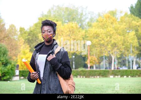 Une étudiante africaine de l'université portant un masque de protection à l'extérieur du campus. Nouvelle norme à l'université. Banque D'Images