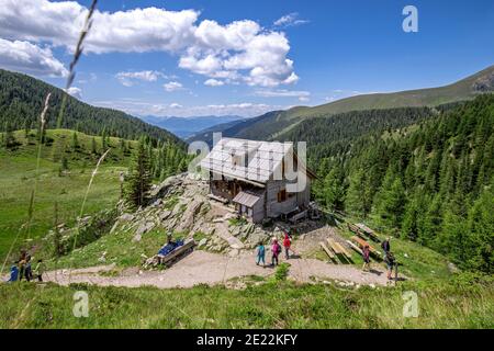 Randonneurs en montagne / randonneurs passant devant la cabane de montagne dans le parc national de Nock Mountains / Nockberge en été, Alpes de Gurktal, Carinthie / Kärnten, Autriche Banque D'Images