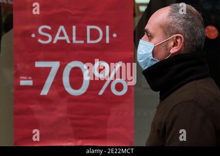 Les ventes commencent en campanie, un homme portant un masque pour lutter contre l'épidémie de COVID-19 marche à côté de la fenêtre d'un magasin dans les rues commerçantes de la ville où un panneau 'sales -70%' est affiché. Banque D'Images