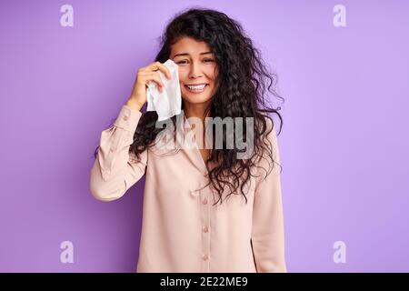 une femme triste se balaye avec une serviette et des cris isolés sur fond violet Banque D'Images