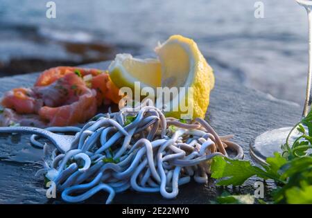 Gros plan de fruits de mer avec citron et verts avec le mer en arrière-plan Banque D'Images