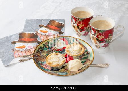 Deux tartes maison à la menthe sur l'assiette de Noël avec une cuillère de crème fraîche, à côté de deux tasses de café crémeux et de serviettes de table. Cuisine de confort en hiver Banque D'Images