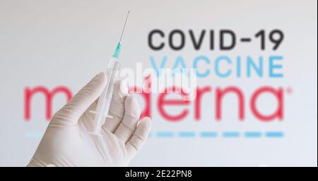 Une main avec un gant tenant une seringue devant le logo Moderna, l'une des sociétés produisant un vaccin Covid-19 (coronavirus). Vienne, Autriche - janvier Banque D'Images