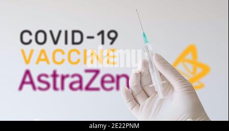 Une main avec un gant tenant une seringue devant le logo d'AstraZeneca, l'une des sociétés produisant un vaccin Covid-19 (coronavirus). Vienne, Autriche - Jan Banque D'Images