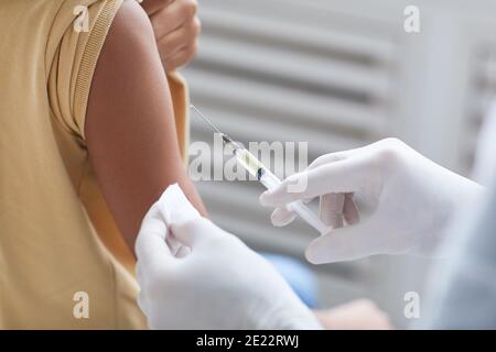 Gros plan d'un médecin méconnaissable qui vaccine un garçon afro-américain, se concentre sur la main tenant la seringue, l'espace de copie Banque D'Images