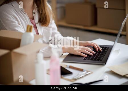 Femme non reconnaissable dropshipper avec ordinateur portable travaillant à la maison, coronavirus concept. Banque D'Images