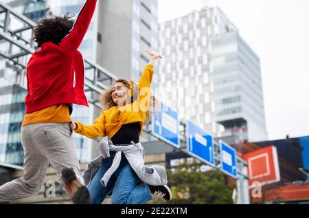 Un jeune couple fait de la vidéo pour les médias sociaux en plein air dans la rue, sautant. Banque D'Images