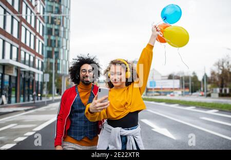 Jeune couple avec smartphone pour la vidéo des médias sociaux en plein air dans la rue. Banque D'Images