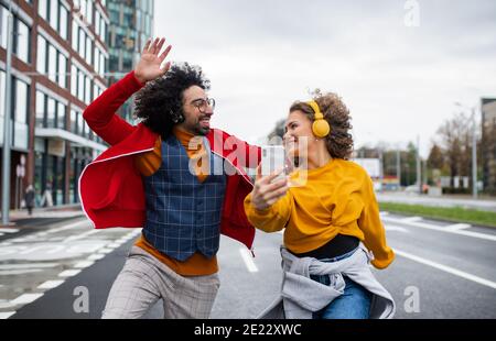 Jeune couple avec smartphone pour la vidéo des médias sociaux en plein air dans la rue. Banque D'Images