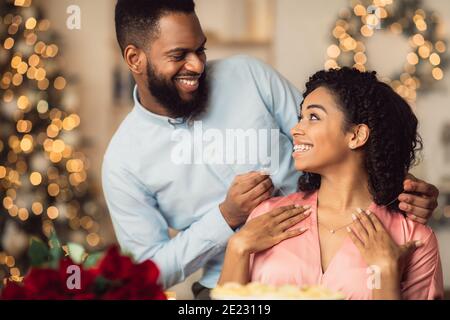 Jeune homme noir souriant portant un collier sur sa femme Banque D'Images