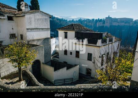 Rue juive de Grenade, Espagne, à midi avec lumière dure et forteresse palais de l'Alhambra à l'arrière. Anciens bâtiments et maisons. Banque D'Images