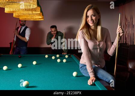 de jeunes amis actifs jouent au billard au bar après le travail, se reposent et se préparent à tirer des boules de billard Banque D'Images