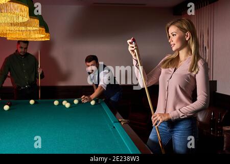 femme se préparant à jouer au billard professionnel dans le club de billard sombre, passer un moment agréable Banque D'Images