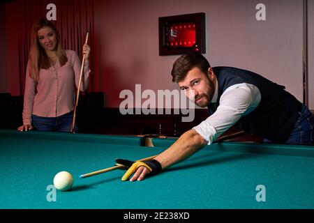 homme jouant au snooker, se douant pour frapper le ballon sur la table de billard de la piscine. agréable passe-temps au bar après le travail Banque D'Images