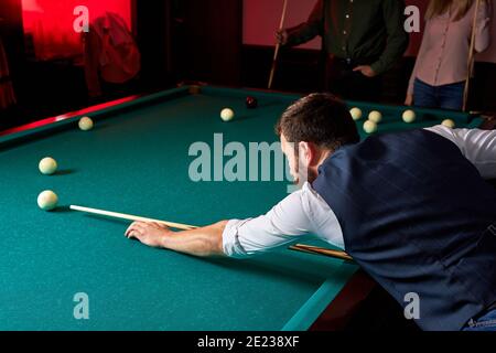 homme jouant au snooker, se douant pour frapper le ballon sur la table de billard de la piscine. agréable passe-temps au bar après le travail Banque D'Images