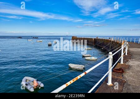 Image de la jetée du port de la Rocque avec des bateaux bleu ciel Avec quelques nuages et la côte de la France sur le horizon Banque D'Images