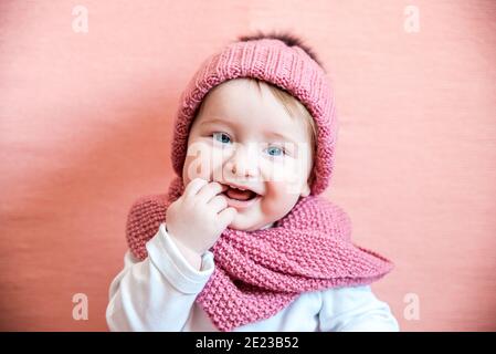 Fille cheveux longs rêve rose fond. Enfant rêve visage vêtements tricotés accessoire. Enfant fille vêtements mignon tricoté chapeau et accessoire foulard. Banque D'Images