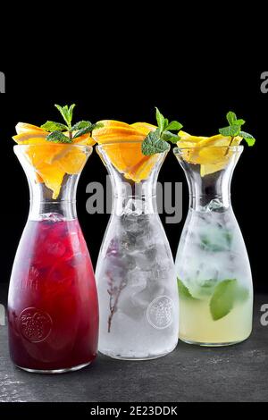 Trois limonades, lime, concombre, fraise, en cruches transparentes, sur fond noir Banque D'Images