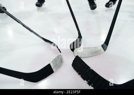 Groupe de bâtons de hockey au milieu du cercle fait plusieurs joueurs debout sur la patinoire et l'entraînement pendant la préparation du jeu Banque D'Images