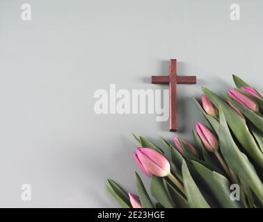 Croix en bois et fleurs de tulipe de printemps fraîches. Temps de résurrection. Concept de l'Église. Vue de dessus. Espace de copie. Banque D'Images