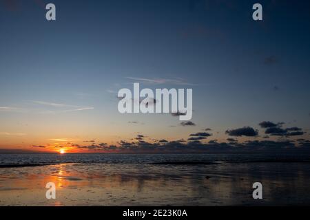 Vue sur le soleil couchant qui brille sur la mer et se reflète sur la plage, nuages avec des bords ensoleillés. Paysage. Photo de haute qualité montrant le concept de liberté et de rêves Banque D'Images
