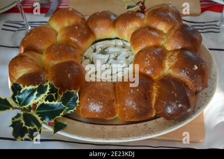 Un camembert entier cuit au four au romarin dans un pain de brioche maison à la croûte dorée. Petits pains français classiques et fromage doux au milieu crémeux Banque D'Images