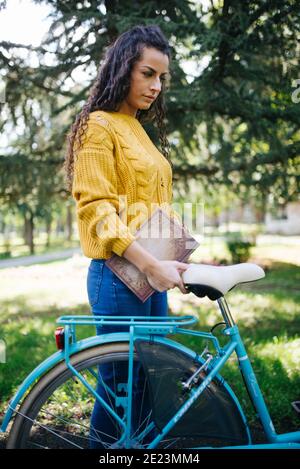 Femme marchant avec son vélo dans la rue en automne. Banque D'Images