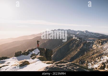 Jeune homme prenant une photo contre la chaîne de montagne enneigée au coucher du soleil, Gredos, Espagne Banque D'Images