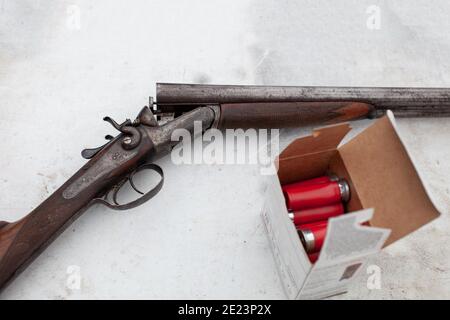 Un ancien fusil de chasse à double corps à action de rupture, vintage, doté de deux déclencheurs et de deux marteaux. Placé sur une table à une aire d'extérieur avec une boîte d'ammuni Banque D'Images