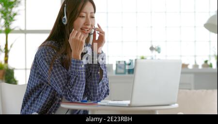 une jeune femme porte un casque et utilise la visioconférence sur un ordinateur portable ordinateur à la maison Banque D'Images