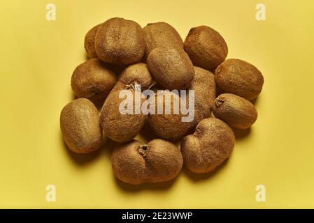 Prise de vue en grand angle d'une pile de kiwis mûrs isolée sur fond jaune Banque D'Images