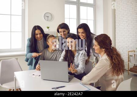 Groupe de jeunes femmes d'affaires souriantes ayant des appels vidéo avec leurs collègues Banque D'Images