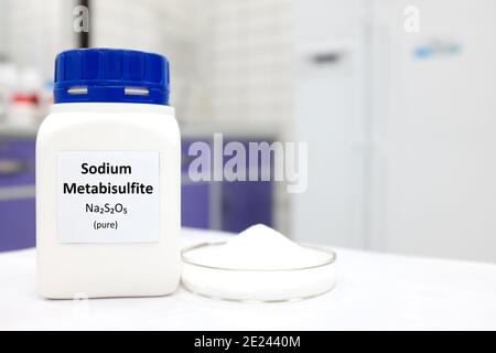 Mise au point sélective d'un flacon d'additif alimentaire de métabisulfite de sodium pur à côté d'une boîte de Petri avec une substance en poudre solide blanche. Laboratoire blanc . Banque D'Images