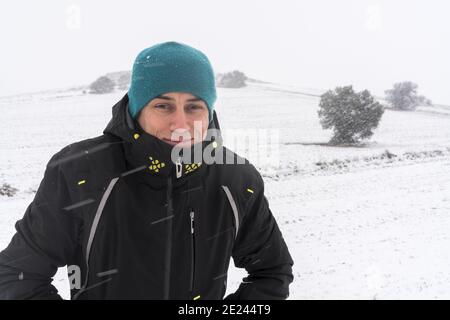 Homme souriant avec un manteau et un chapeau, au milieu d'une chute de neige. Espagne. Banque D'Images