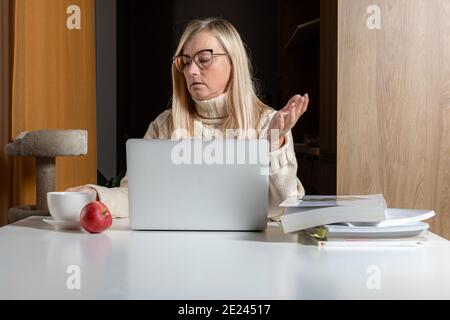 Choqué moyenne d'âge mature femme se sentant stressée lire incroyable en ligne actualités Banque D'Images