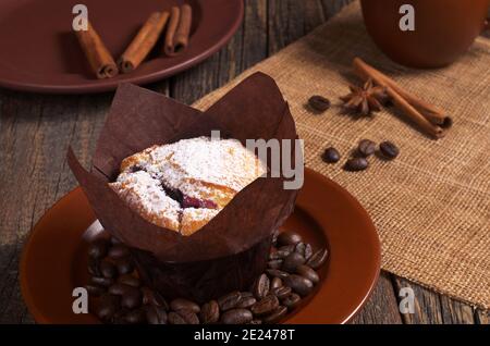 Muffin dans du papier ciré avec des bleuets et une tasse de café une table en bois sombre Banque D'Images
