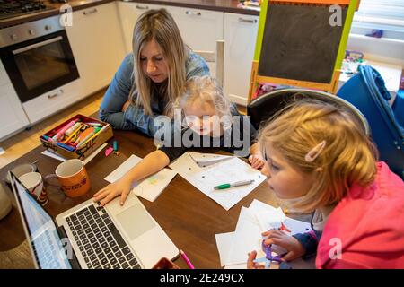 Les filles de 3 et 5 ans qui font l'école travaillent avec leur mère à la maison pendant la fermeture de l'école Covid. Banque D'Images