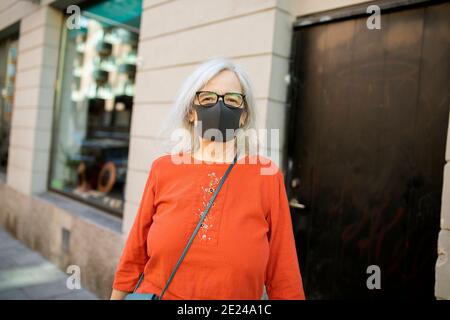 Femme portant un masque facial regardant l'appareil photo Banque D'Images