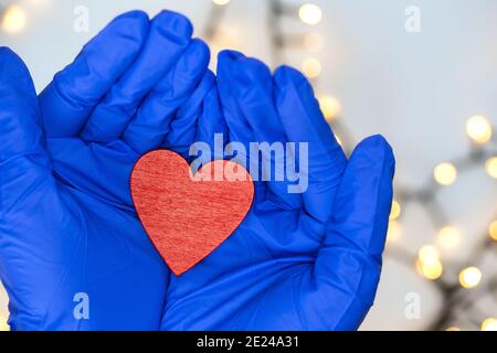 Deux gants médicaux bleus de protection tenant un coeur rouge pour Hope Covid-19 et concept de santé. Coronavirus, virus et arrière-plan médical vue du dessus Banque D'Images