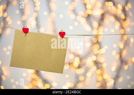 Lettre vierge, enveloppe ou carte de voeux accrochée à cœur rouge, lettre romantique d'amour, fond de bokeh concept de jour de la Saint-Valentin, espace de copie Banque D'Images
