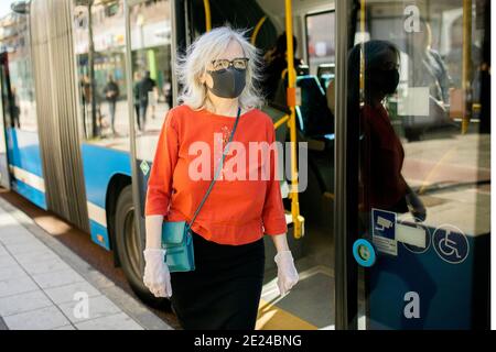 Femme portant un masque facial près du bus Banque D'Images