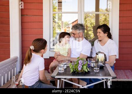 Parents avec deux filles assises devant la maison Banque D'Images