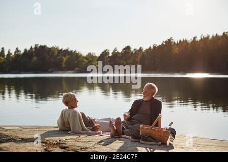 Couple souriant ayant pique-nique au lac Banque D'Images